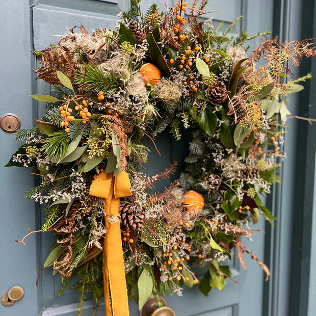 Close-up of the Spiced Clementine Luxury Winter Wreath showcasing dried clementines, golden berries, and rustic accents like thistle and bracken.